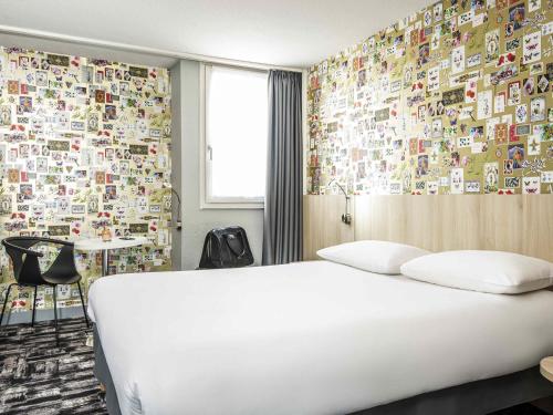 a bedroom with a white bed and a wall covered in stickers at Ibis Styles Reims Centre in Reims
