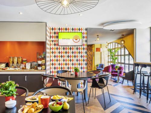 a restaurant with tables and chairs and a counter at Ibis Styles Reims Centre in Reims