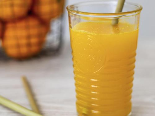 a glass of orange juice on a table at Ibis Styles Reims Centre in Reims
