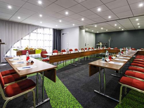 a conference room with long tables and red chairs at Ibis Styles Reims Centre in Reims