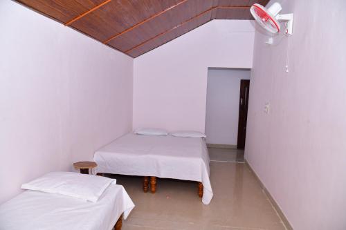 two beds in a room with white walls at SugarLeaf Homestay - Home Food & Near to Tourist Places in Sakleshpur