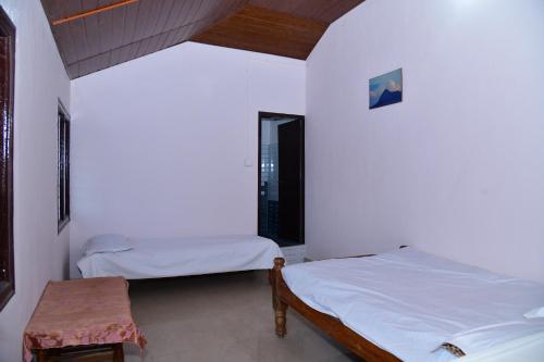 two beds in a room with a table and a window at SugarLeaf Homestay - Home Food & Near to Tourist Places in Sakleshpur