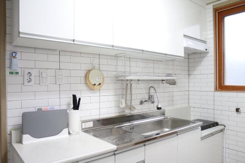 a kitchen with a stainless steel sink and white tiles at Bitdamjip Near Hwaseong Fortress and Suwon Station in Suwon
