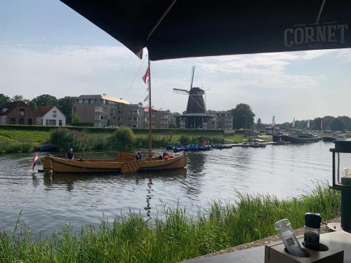 a couple of boats on a river with a windmill at Romantisch Wellness Appartement met privé Hottub Sauna Gamesroom in Den Ham
