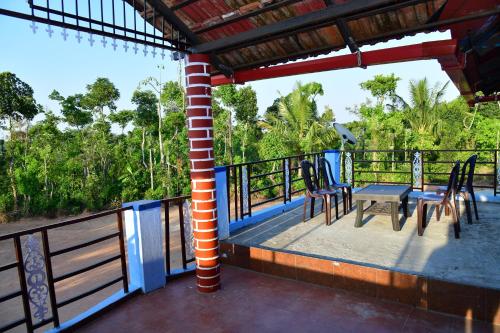 a porch with chairs and a table on a balcony at SugarLeaf Homestay - Home Food & Near to Tourist Places in Sakleshpur