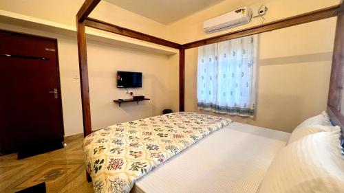 a bedroom with a bed and a tv and a window at Athiratha Living in Malpe