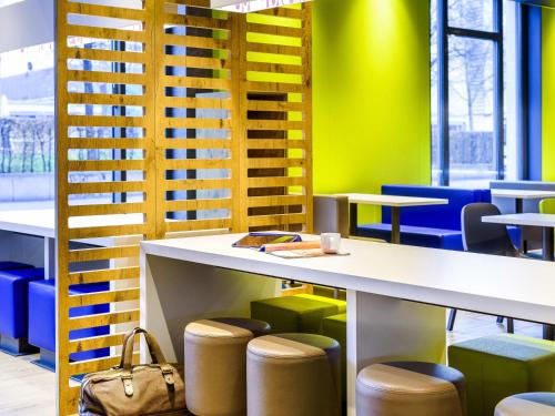 a table and stools in a room with yellow and blue at ibis budget Hamburg City in Hamburg