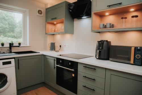 a kitchen with green cabinets and a stove top oven at Spacious Flat with Parking Great Inverness Base in Inverness