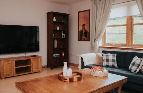 a living room with a couch and a table and a tv at Spacious Flat with Parking Great Inverness Base in Inverness