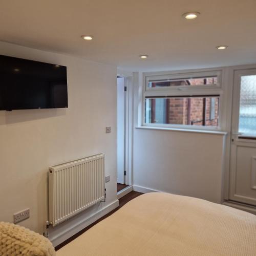 a bedroom with a flat screen tv and a window at Welcoming ensuite bedroom in Wolverhampton