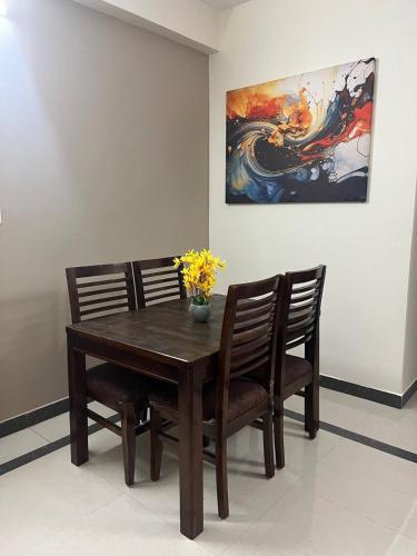 a dining room table with two chairs and a painting at Premium 2BHK-Gachibowli -Walk to AIG Microsoft DLF in Gachibowli