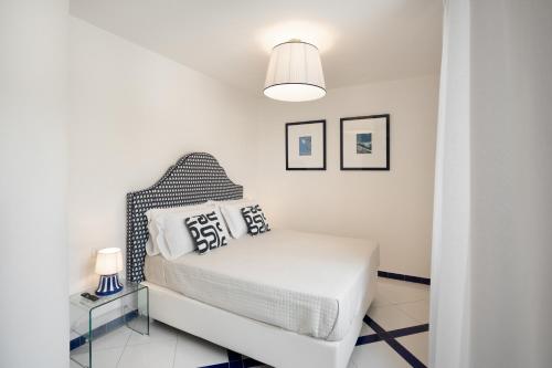 a white bedroom with a bed and a lamp at Torre Paradiso in Minori