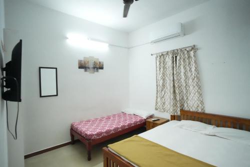 a bedroom with two beds and a bench in it at LeBeach Villa, Luxurious Stay Opposite Auroville Beach, ECR Road in Kuilapayam
