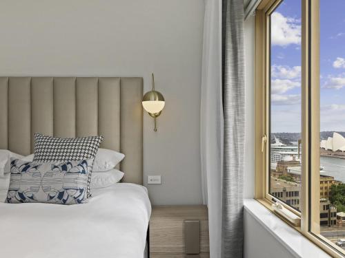 a bedroom with a bed and a large window at The Sebel Quay West Suites Sydney in Sydney