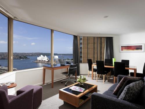 a living room with a view of a boat in the water at The Sebel Quay West Suites Sydney in Sydney
