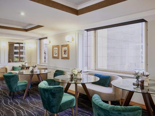 a restaurant with two tables and green chairs at The Sebel Quay West Suites Sydney in Sydney