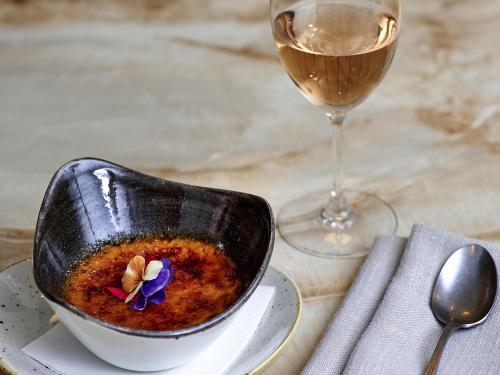 a bowl of soup next to a glass of wine at The Sebel Quay West Suites Sydney in Sydney