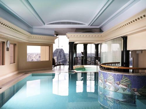 a swimming pool in a building with a view at The Sebel Quay West Suites Sydney in Sydney