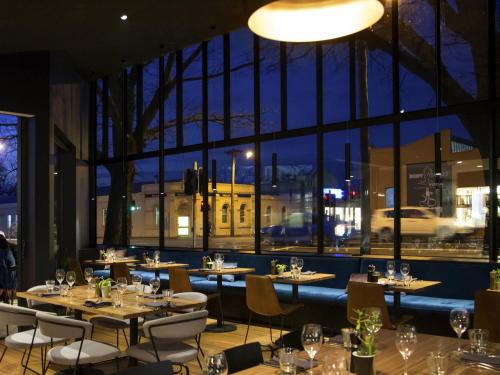 a restaurant with tables and chairs and a large window at The Sebel Launceston in Launceston