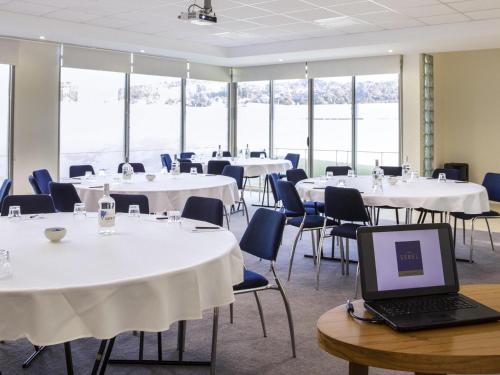 a room with tables and chairs and a laptop on a table at The Sebel Launceston in Launceston