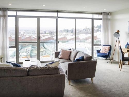 a living room with a couch and a large window at The Sebel Launceston in Launceston