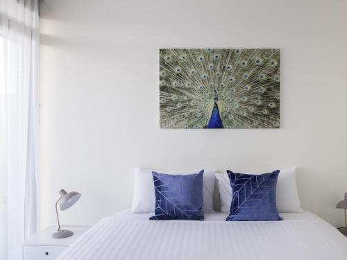 a bedroom with a white bed with blue pillows at The Sebel Launceston in Launceston