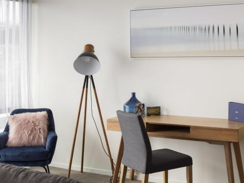 a desk and two chairs in a room with a lamp at The Sebel Launceston in Launceston