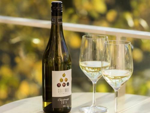 a bottle of white wine next to two wine glasses at The Sebel Launceston in Launceston