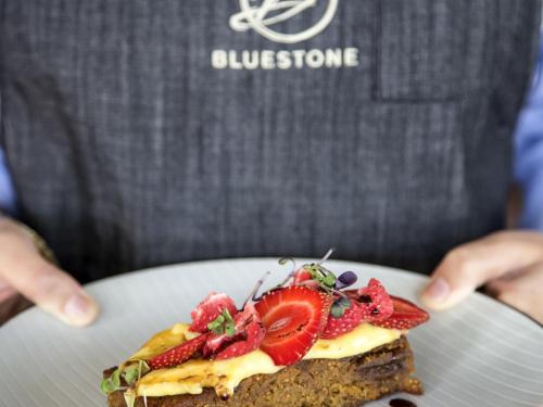 a person holding a piece of food with strawberries on it at The Sebel Launceston in Launceston