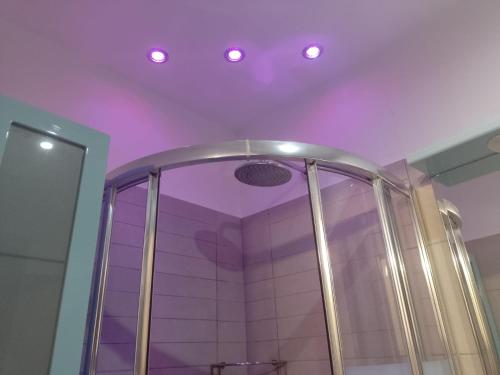 La salle de bains est pourvue d'une douche avec des lumières violettes au plafond. dans l'établissement B&B Corte del Centro, à Novate Milanese