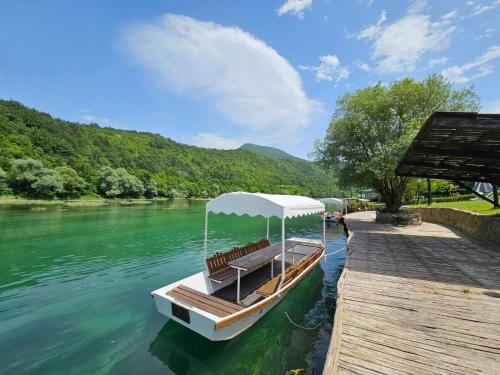 a boat with a canopy on the side of a river at Turističko naselje Natura Art-Hotel Opal Art in Lohovo