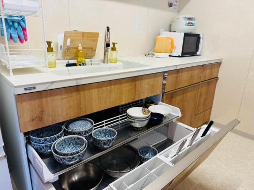 a kitchen with pots and pans in an open refrigerator at Capsule Hostel Beppu Tower in Beppu