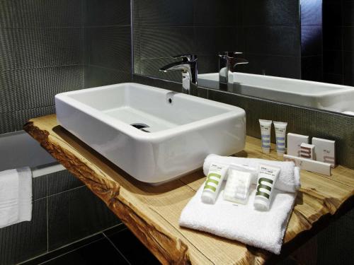 a bathroom with a white sink on a wooden counter at Mercure Brignoles Golf de Barbaroux & Spa in Brignoles
