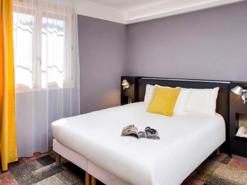 a bedroom with a bed with two shoes on it at ibis Styles Roanne Centre Gare in Roanne