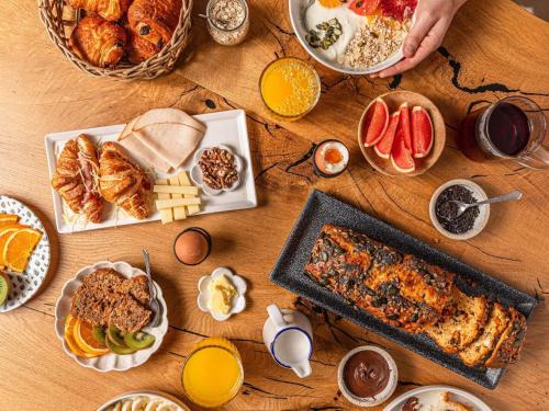 a wooden table with breakfast foods and drinks on it at ibis Styles Roanne Centre Gare in Roanne