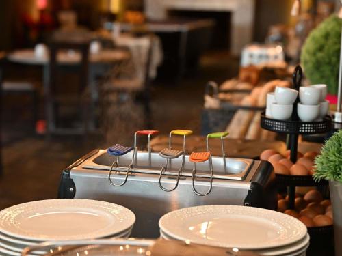 a counter with plates and utensils on top of a stove at Mercure Brignoles Golf de Barbaroux & Spa in Brignoles