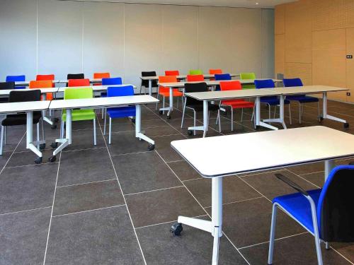 an empty classroom with tables and colorful chairs at Mercure Brignoles Golf de Barbaroux & Spa in Brignoles