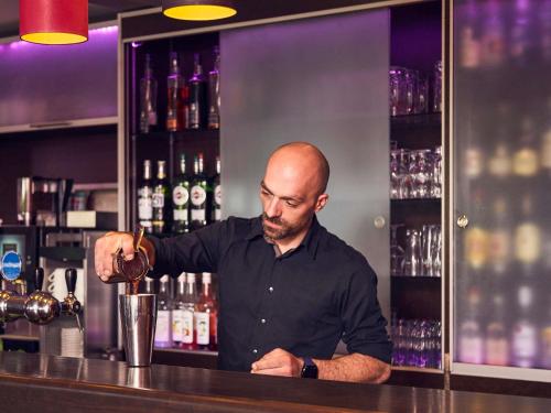 a man standing at a bar making a drink at Mercure Brignoles Golf de Barbaroux & Spa in Brignoles