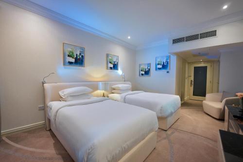 a hotel room with two beds and a couch at Grand Regency Doha, Trademark Collection by Wyndham in Doha