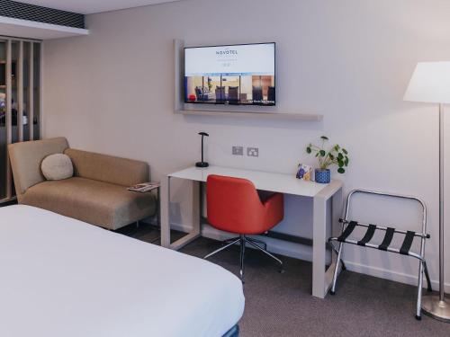 a room with a desk and a chair and a bed at Novotel Newcastle Beach in Newcastle