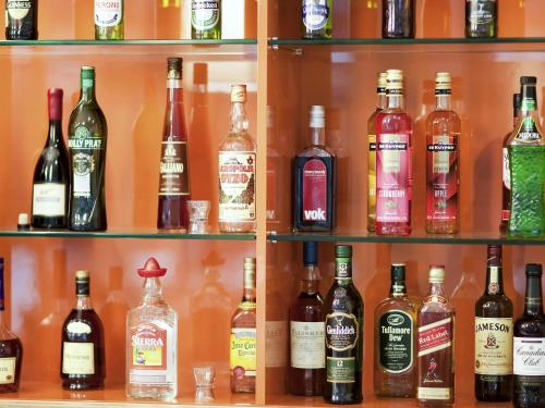 a shelf filled with lots of bottles of alcohol at Novotel Newcastle Beach in Newcastle