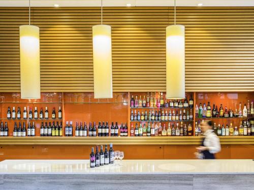 a man walking past a bar with bottles of wine at Novotel Newcastle Beach in Newcastle