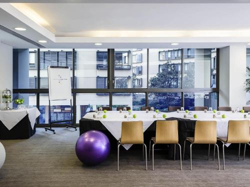 a conference room with a table and chairs and a whiteboard at Novotel Newcastle Beach in Newcastle