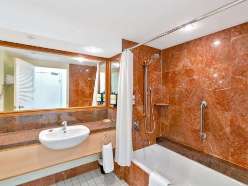 a bathroom with a tub and a sink and a shower at Pullman Cairns International in Cairns