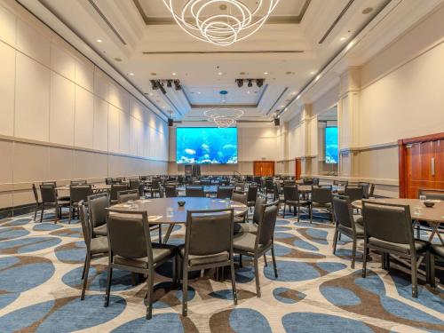 a conference room with tables and chairs and a projection screen at Pullman Cairns International in Cairns