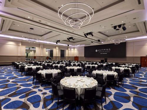 a banquet hall with white tables and black chairs at Pullman Cairns International in Cairns