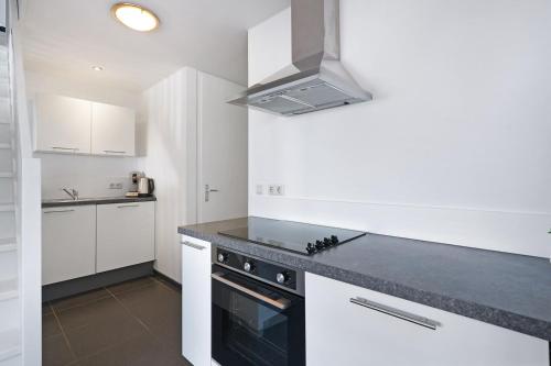 a kitchen with white cabinets and a stove top oven at Weststraat 22 - Ouddorp - Appartement Oost 3P in Ouddorp