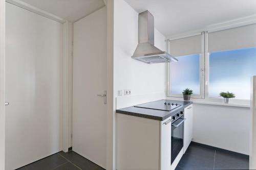a white kitchen with a stove top oven next to a window at Weststraat 22 - Ouddorp - Appartement Oost 3P in Ouddorp