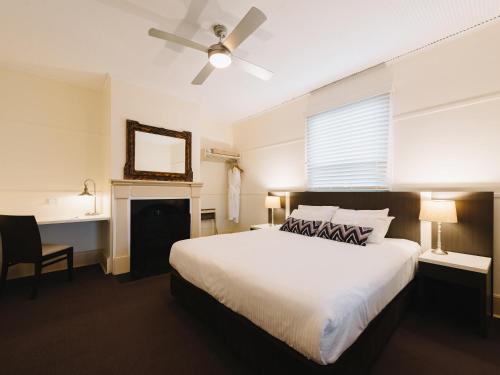 a bedroom with a white bed and a ceiling fan at Q Station in Sydney