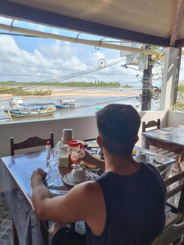 Ein Mann, der an einem Tisch mit Blick auf den Ozean sitzt in der Unterkunft Pousada Nativa - Ilha de Boipeba in Ilha de Boipeba